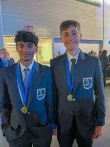 Students in formal suits wearing DECA medals at Albuquerque Academy event.