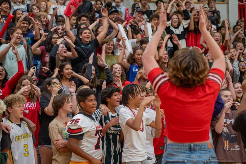 Albuquerque Academy students cheering at school event, diverse group engaging in school spirit activities.