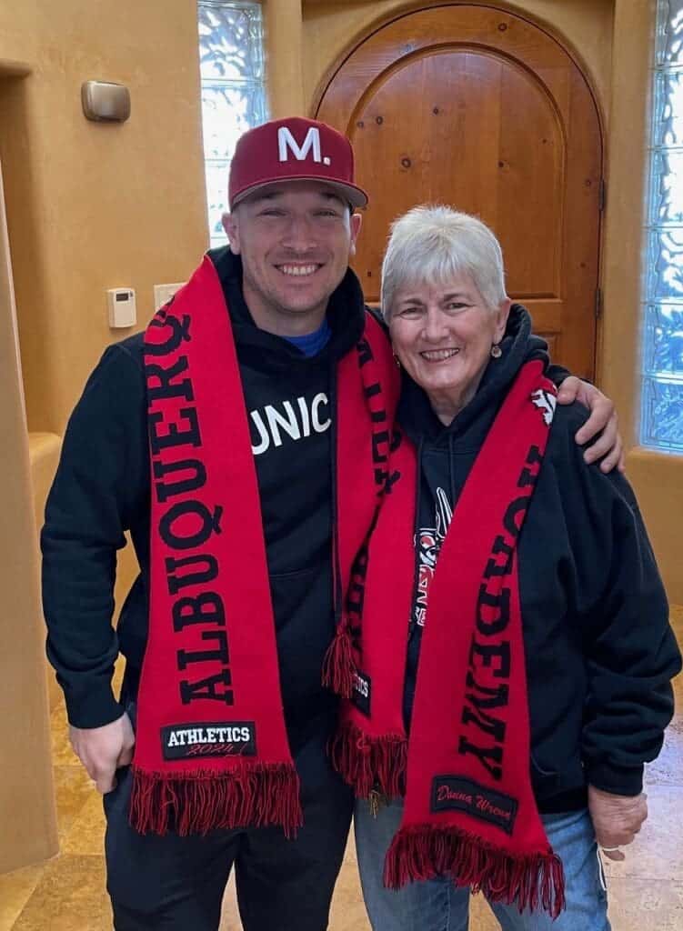 Albuquerque Academy students celebrating sports achievements, wearing school scarves and hats indoors.