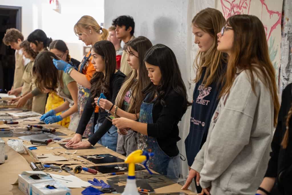 Students engaged in an art class at Albuquerque Academy, creating creative projects with various tools in a collaborative environment.