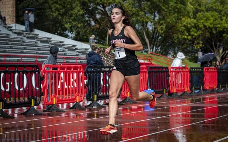ABQ Academy female track athlete running on rainy outdoor track during competition.