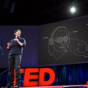 Albuquerque Academy student giving a TED Talk on stage with a visual diagram of head and tech elements.