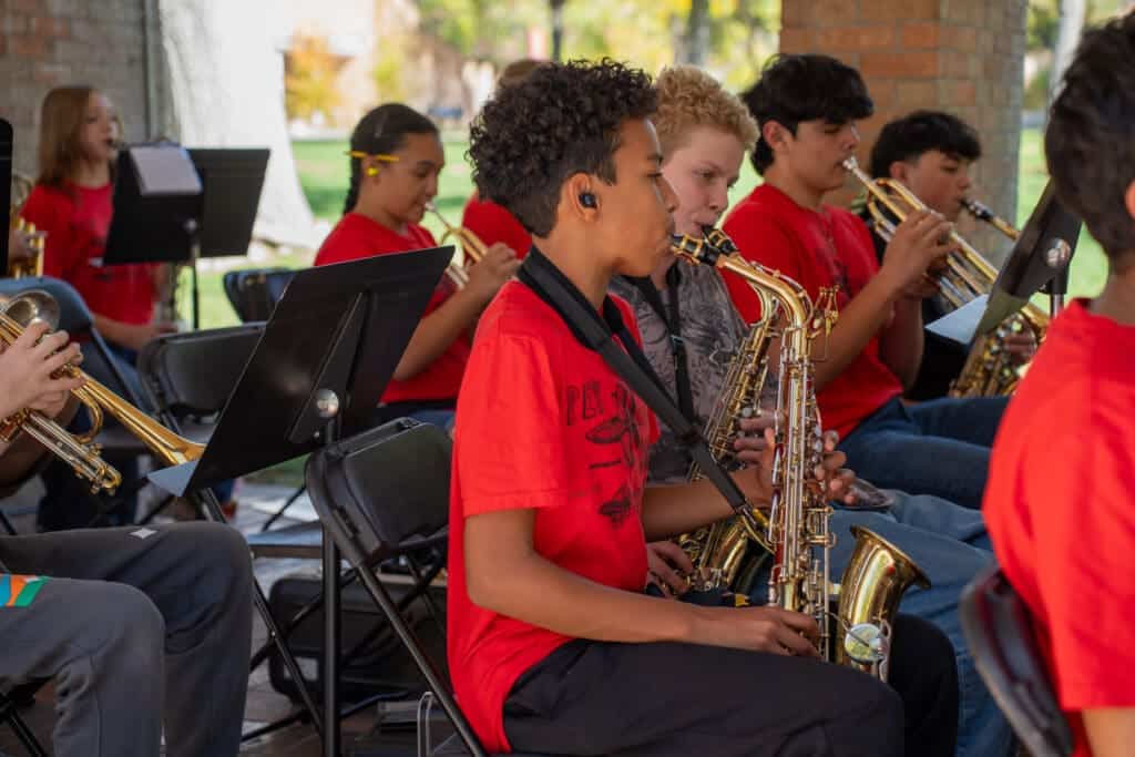 Young students playing saxophones in a band outdoors at Albuquerque Academy, promoting music education and student engagement.