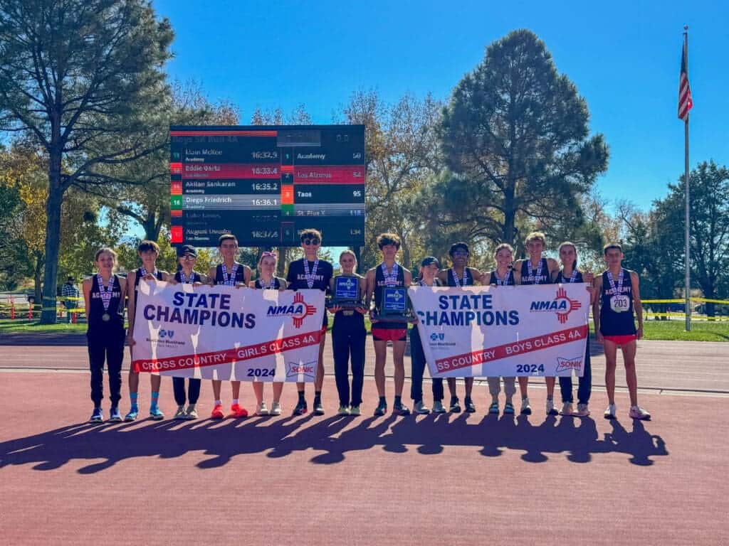 Albuquerque Academy cross country team celebrating state championships outdoors.