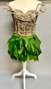 Clothing mannequin dressed with natural tree bark, leaves, and greenery for innovative eco-friendly fashion display.
