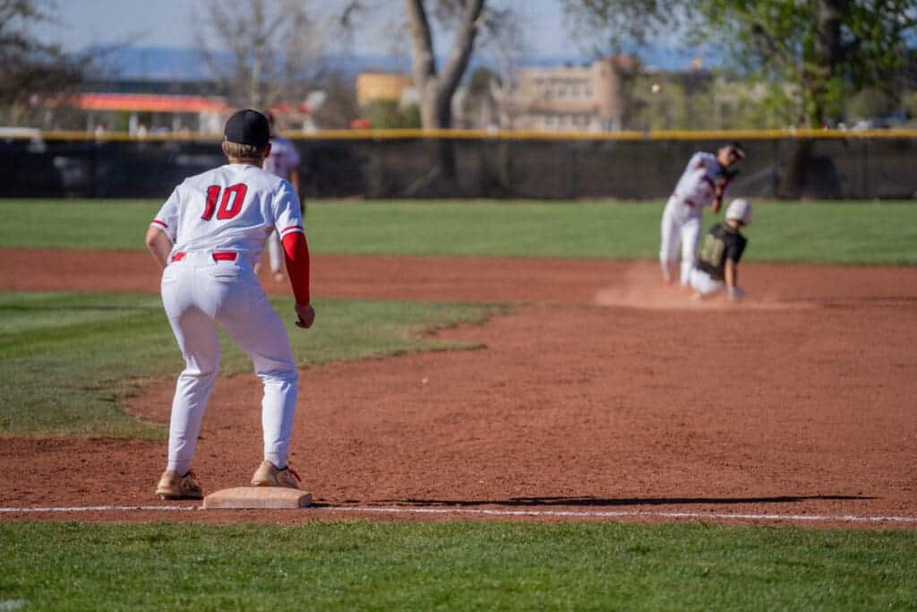 Baseball player wearing number 10 on team at Albuquerque Academy baseball game.