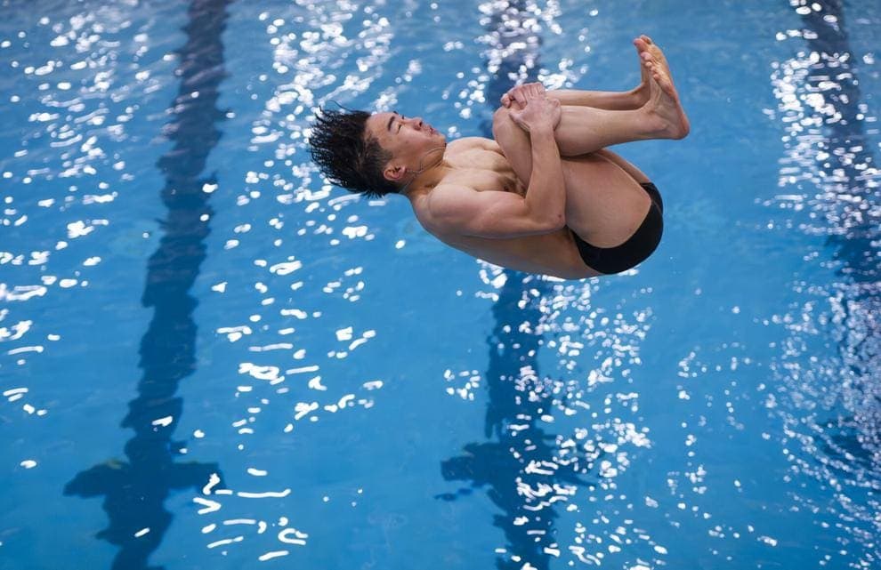 Albuquerque Academy student performing a gymnastics dive in a swimming pool.