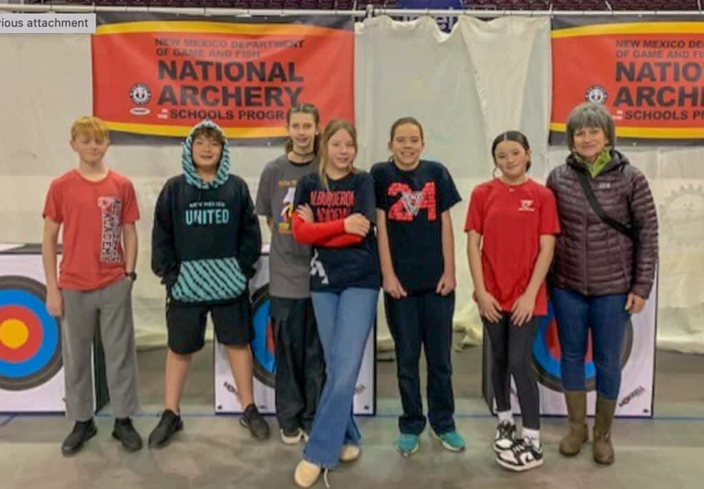Albuquerque Academy students at archery event with National Archery in Schools Program banner.