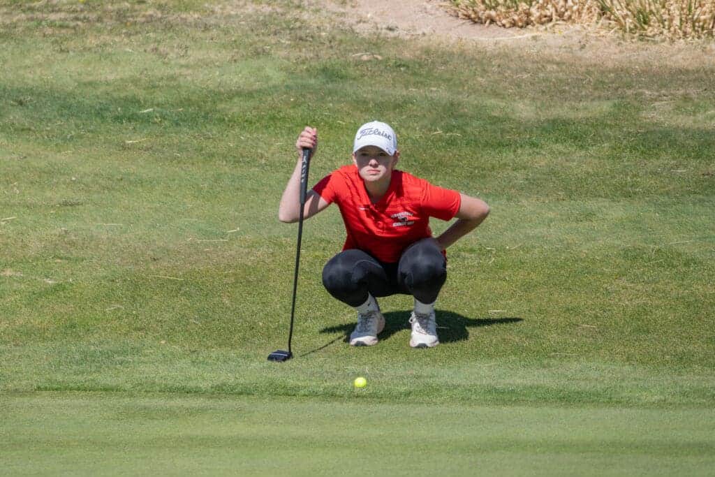 Albuquerque Academy student playing golf on a lush green course.