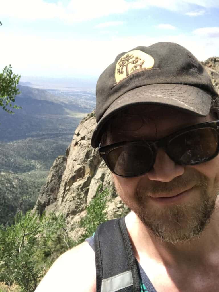 Scenic view of mountain landscape with hiker taking a selfie on a trail.