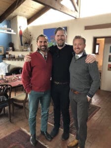 Smiling men in a cozy, decorated home interior, celebrating friendship, with warm lighting and festive decor.