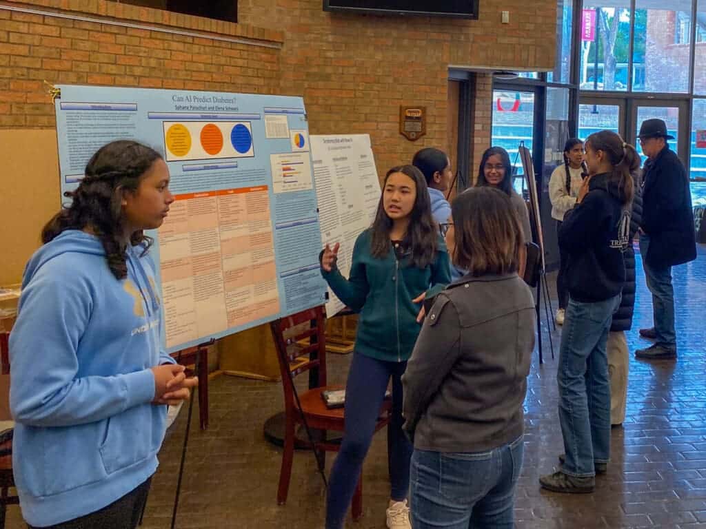 Albuquerque Academy students presenting their research project on diabetes prediction at a science fair or academic event.