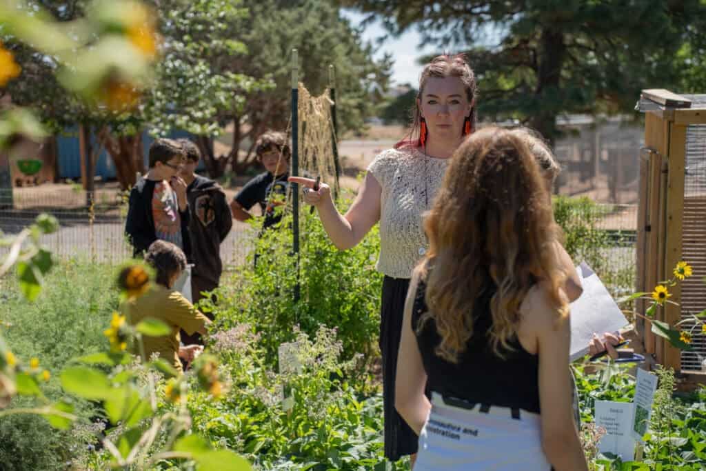 Albuquerque academy students and teacher engaging in outdoor garden learning session.