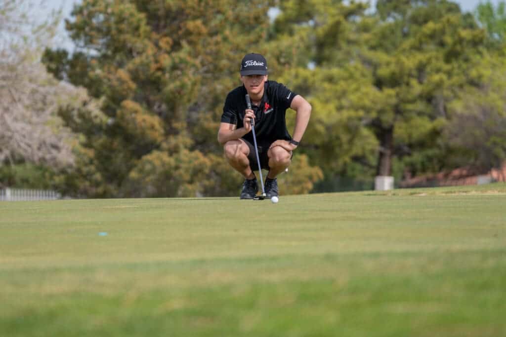Albuquerque academy student playing golf on a lush green course outdoors.
