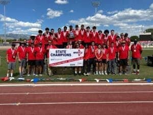 Albuquerque Academy track team celebrating state championships on the field in red uniforms.