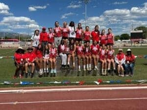 Female track and field team celebrating victory at Albuquerque Academy sports event.