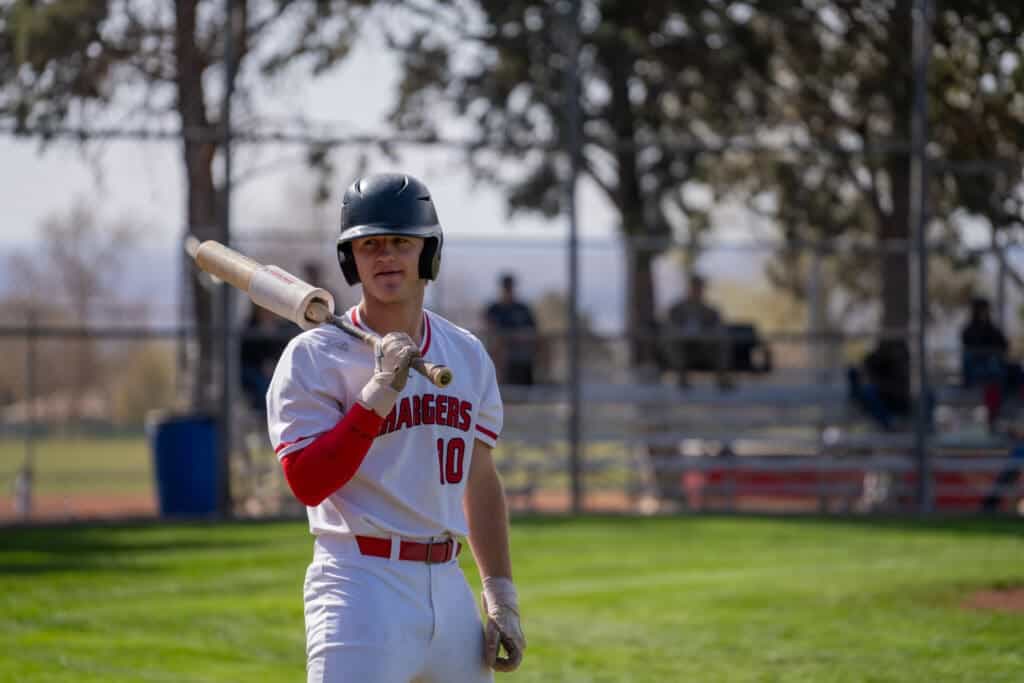 Youth baseball player holding a bat on the field during a game at Albuquerque Academy.