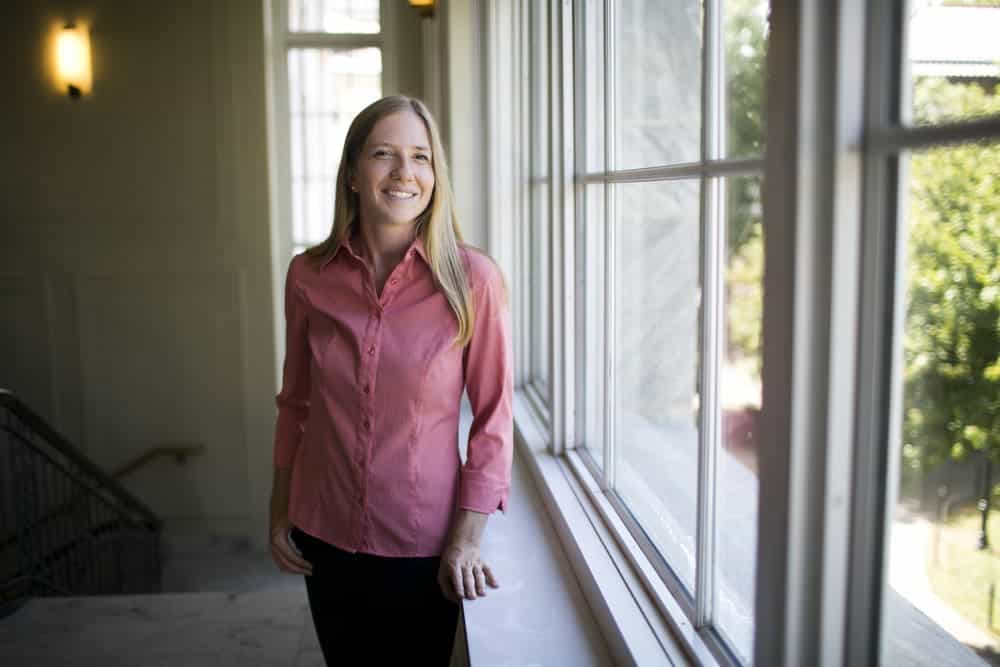 High school teacher smiling by large window at Albuquerque Academy.