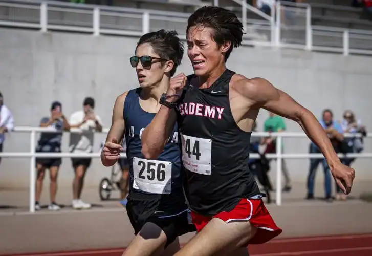 Albuquerque Academy students competing in track and field during a race on an outdoor track.