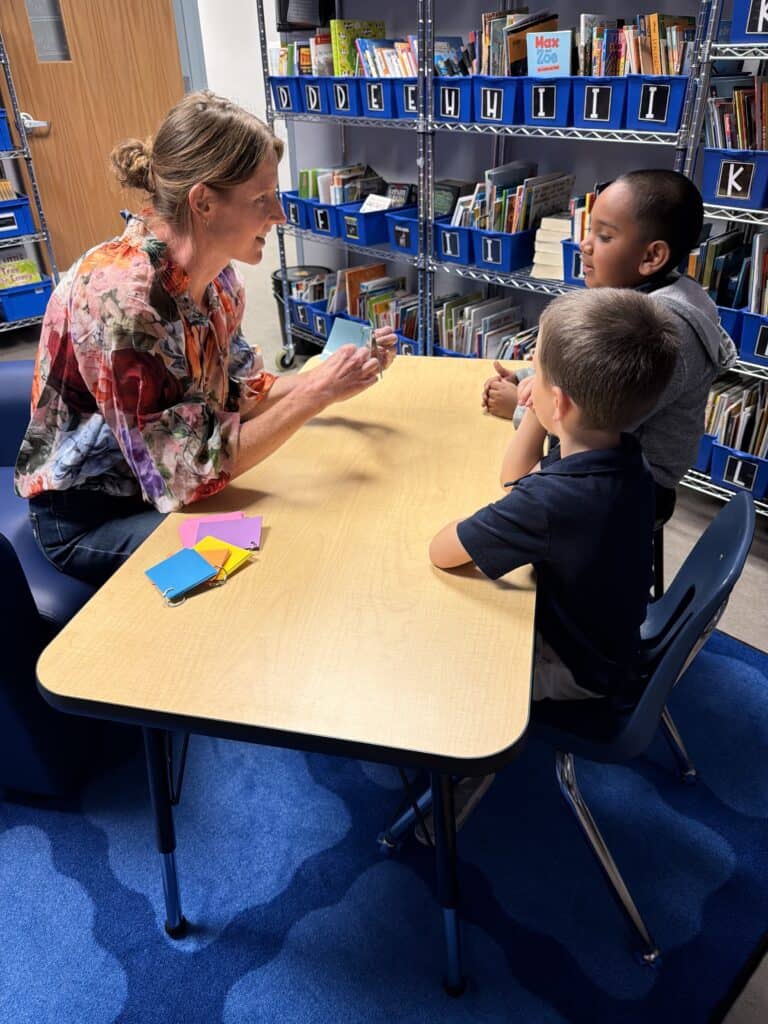 Primary school teacher talking to students in the Albuquerque Academy library, promoting literacy and learning.