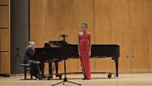 Albuquerque Academy student performing a vocal solo with piano accompaniment on stage.