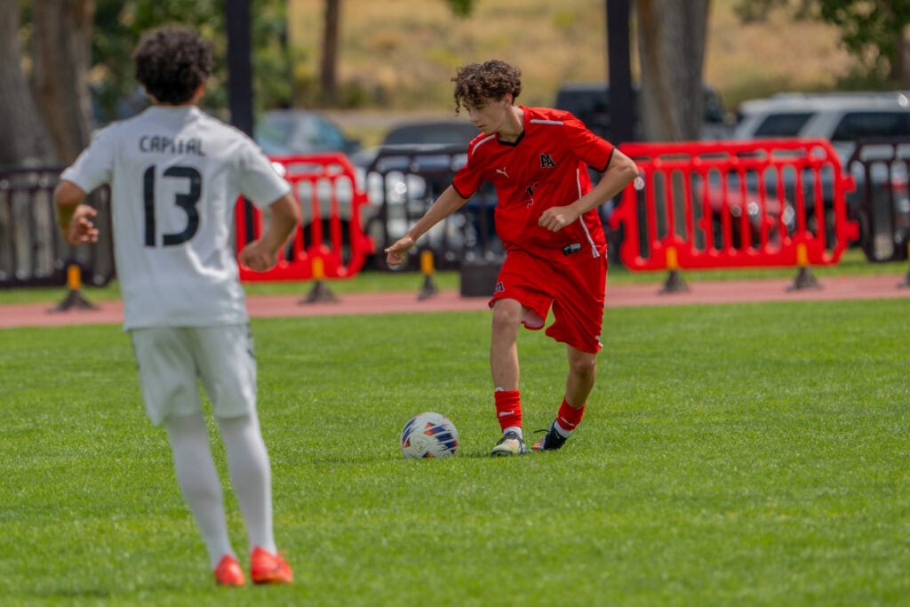 Albuquerque Academy students playing soccer on a grassy field during school sports activity.
