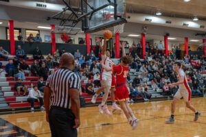 Albuquerque Academy basketball game in a gymnasium with students, spectators, and a player jumping for a shot.