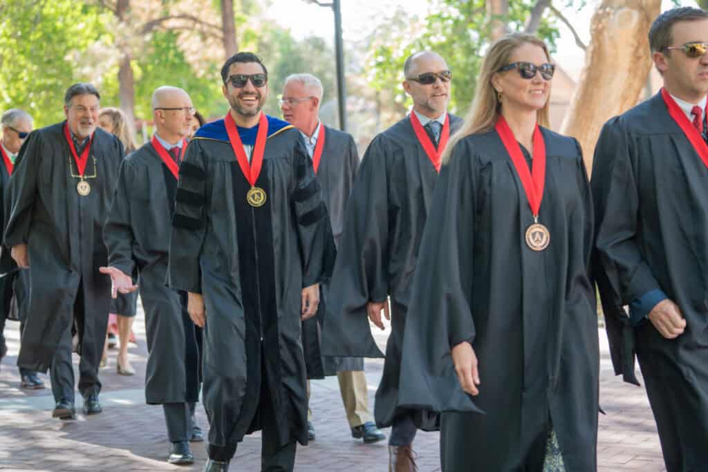 Graduates in academic regalia at Albuquerque Academy graduation ceremony outdoors.