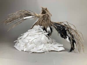 A sculpture made of plastic utensils and natural branches, highlighting environmental sustainability concepts.