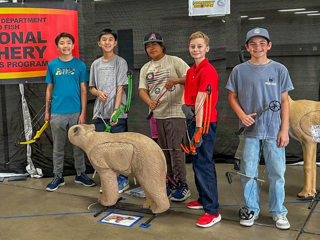A young group of students at Albuquerque Academy participating in archery training indoors.