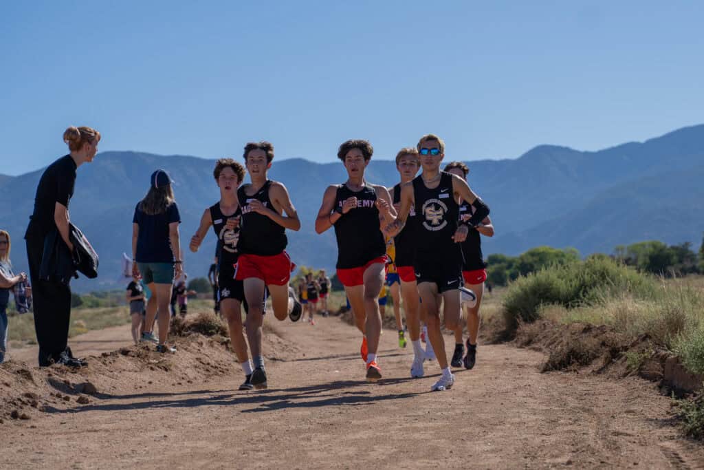 Albuquerque Academy cross country team running outdoors in a scenic mountain landscape.