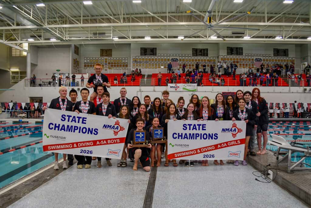 Albuquerque Academy swim team celebrating state championship victory at an indoor pool.