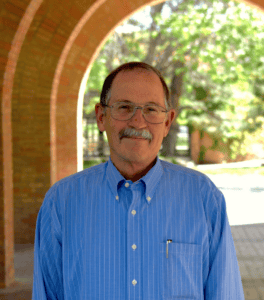 Alumni smiling man outdoors at Albuquerque Academy campus, sunny day.