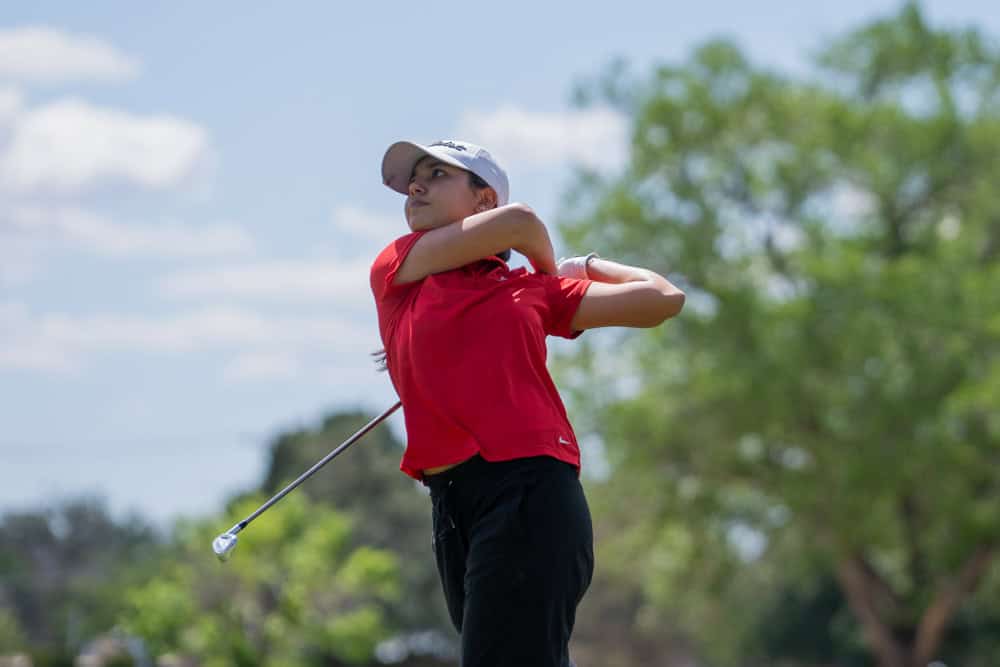 Albuquerque Academy student swinging golf club during match at Arroyo del Oso field.