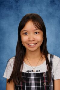 Albuquerque Academy student smiling in classroom with blue background.