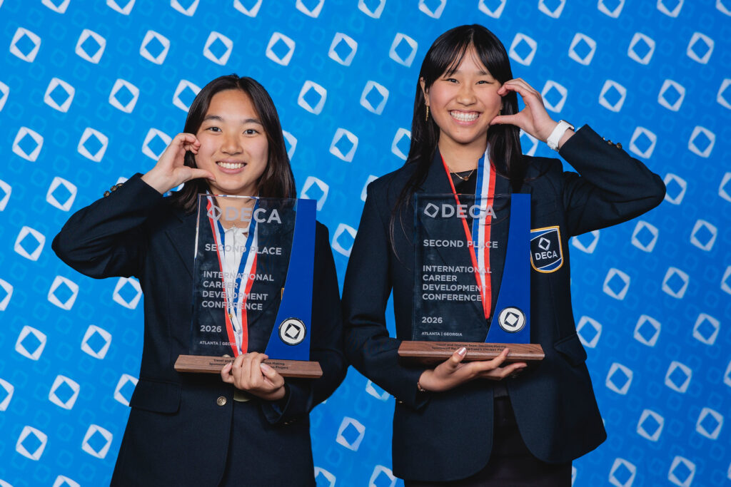 Two students holding DECA second-place trophies