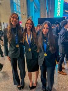 Three students wearing medals at formal event