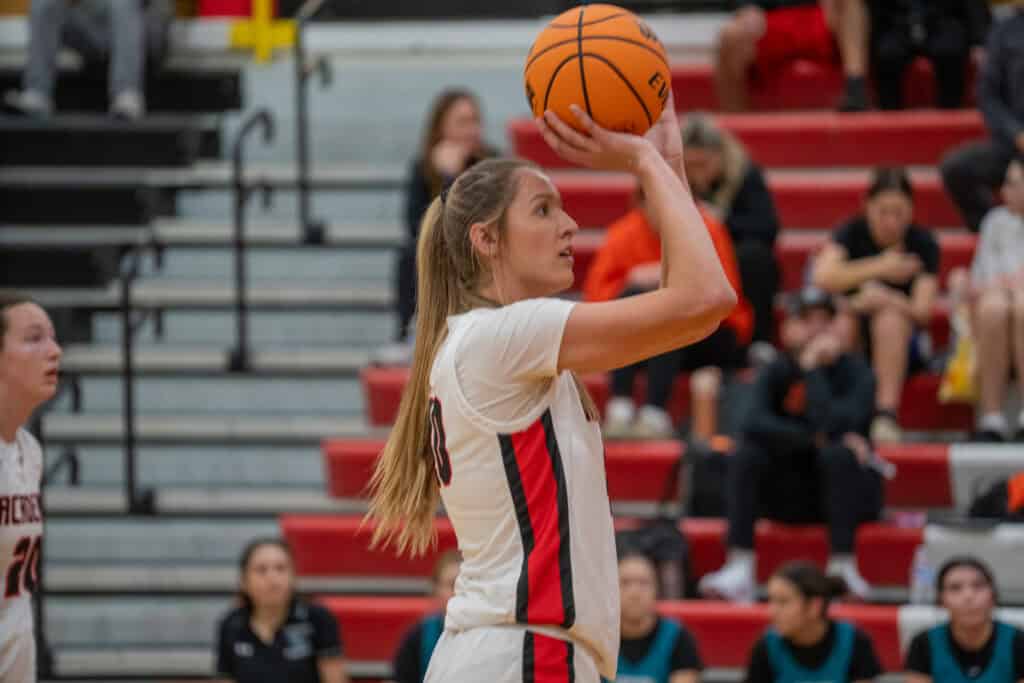 Albuquerque Academy female volleyball player preparing to serve in gymnasium.