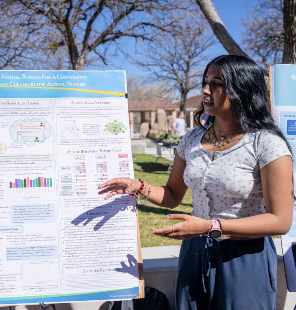 A woman presenting a research poster outdoors at Albuquerque Academy campus.