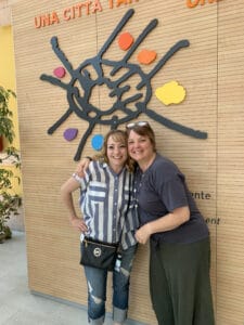 Albuquerque Academy staff members smiling in front of colorful wall art at the school.
