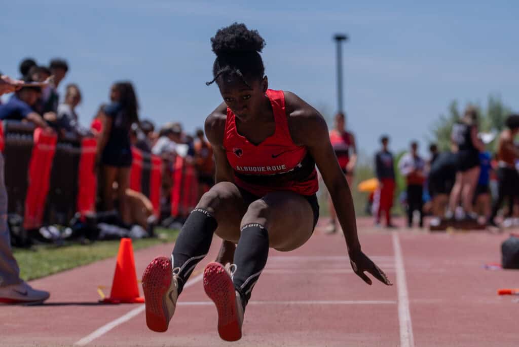 Albuquerque Academy girl athlete competing in track and field event outdoors.