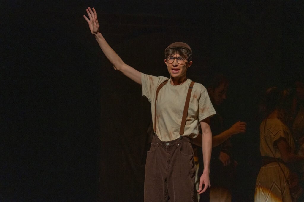 A young actor in costume performs on stage during URINETOWN musical at Albuquerque Academy.