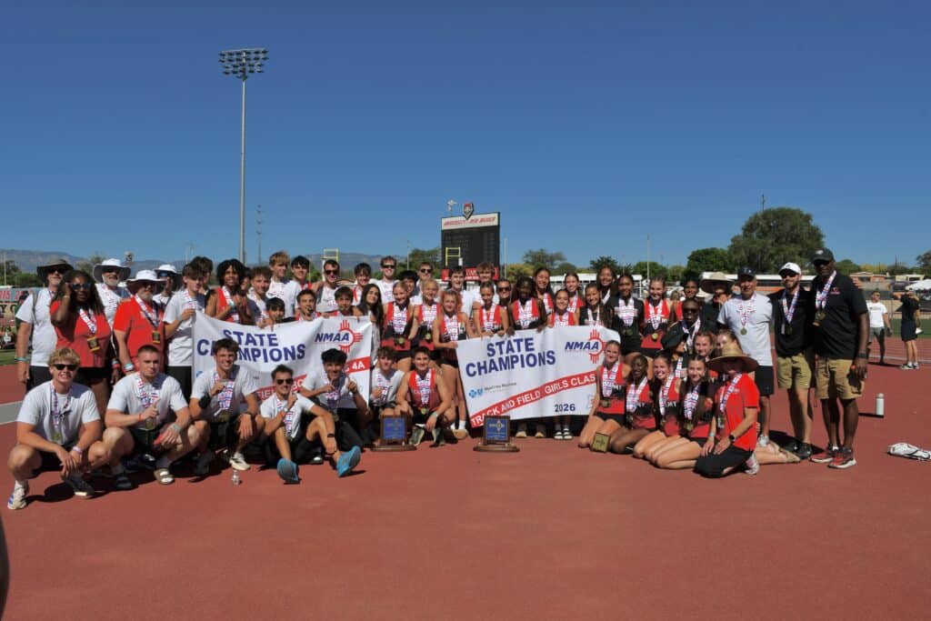 Albuquerque Academy track team celebrating state championship victory outdoors.