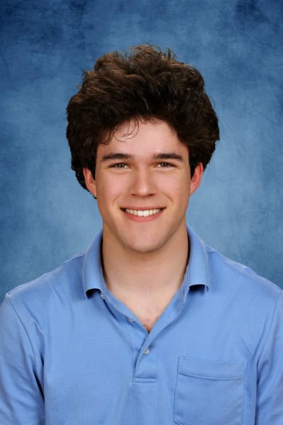 A smiling young male student in a blue shirt at Albuquerque Academy campus.