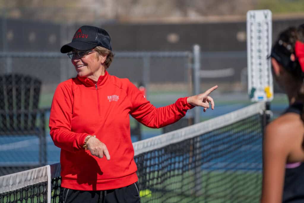 Albuquerque Academy tennis coach Badger giving instructions on the court.