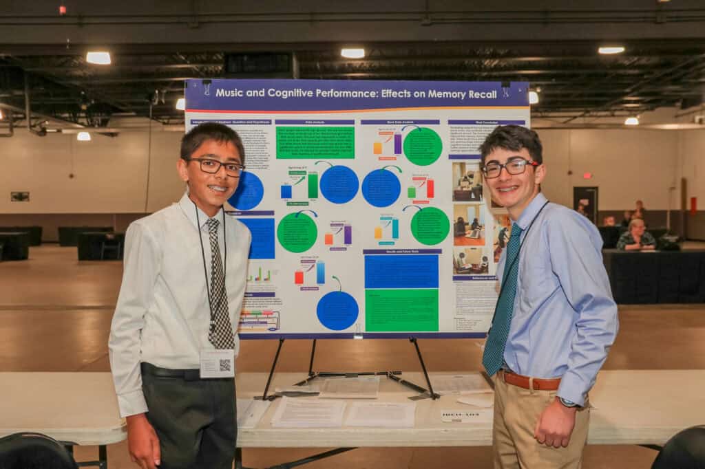 Two students presenting a research poster on memory recall at a science fair.
