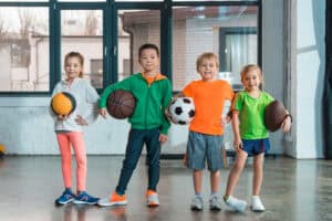 Children holding sports balls in a gym at Albuquerque Academy for Fall activities.