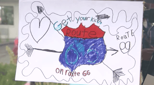 Colorful hand-drawn Route 66 sign with arrows and text about getting your kicks.