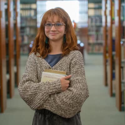 Aurelia DSC09739 Student in library holding a book at Albuquerque Academy.