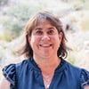 Smiling woman in blue shirt outdoors at Albuquerque Academy campus.